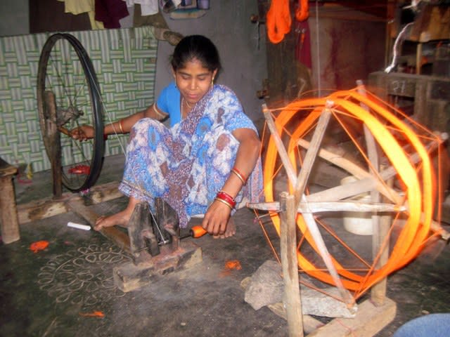 A weaver working on the charkha to create thread yarn to be used as weft.